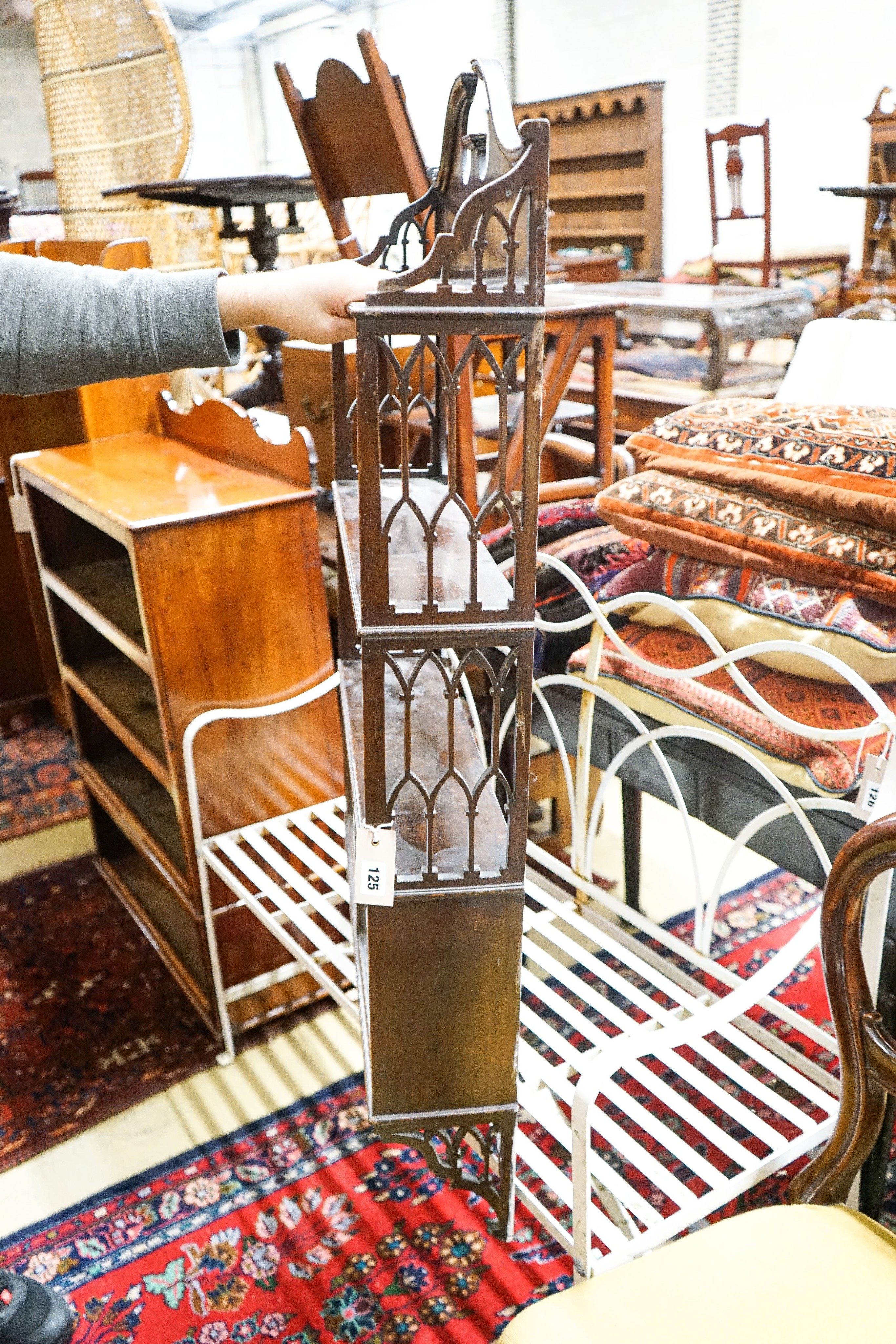 A 19th century Gothic style mahogany three-tier wall bracket with a small glazed cupboard under, width 62cm, depth 15cm, height 108cm